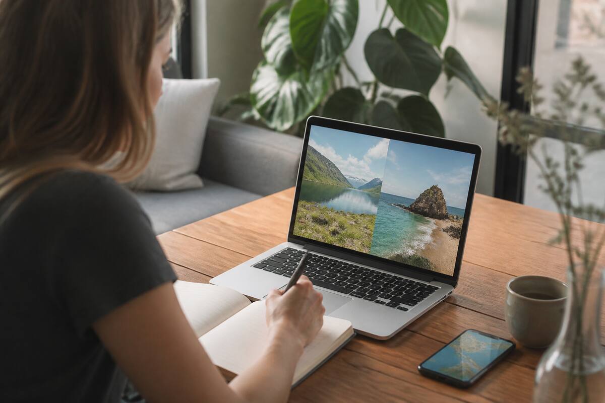 Iemand vergelijkt vakantie-opties op laptop en smartphone aan een tafel, realistische foto zonder tekst in beeld.